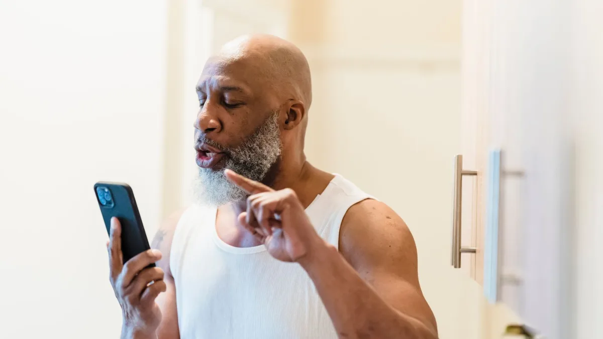 Man looking at a smartphone and gesturing to dismiss a call