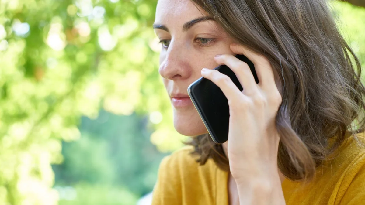 Woman holding a smartphone to her ear outdoors