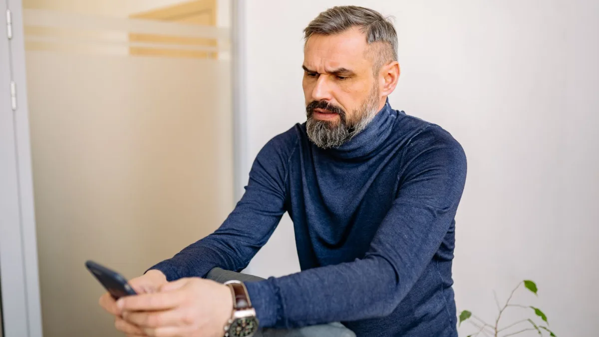 Concerned man looking at a smartphone at home
